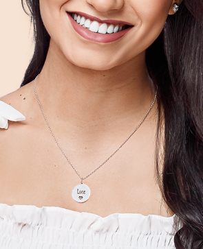 Mulher sorrindo, ela usa colar de prata escrito luz