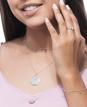 Mulher com várias joias religiosas: choker e pulseira com pingente de cruz, medalha religiosa, anel tercinho