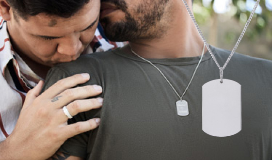 Casal em um momento carinhoso, um usa aliança de namoro e o outro usa um colar com plaquinha, com os nomes do casal gravados.