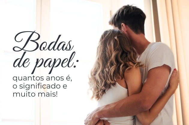 Texto escrito na cor preta: Bodas de papel: quantos anos é, o significado e muito mais! à direita casal, ambos de branco se abraçando próximo a uma cortina.