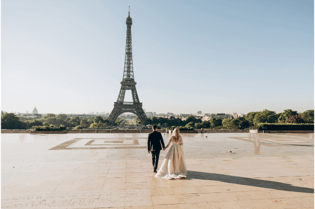 Casal com trajes de casamento em frente à Torre Eiffel, em Paris