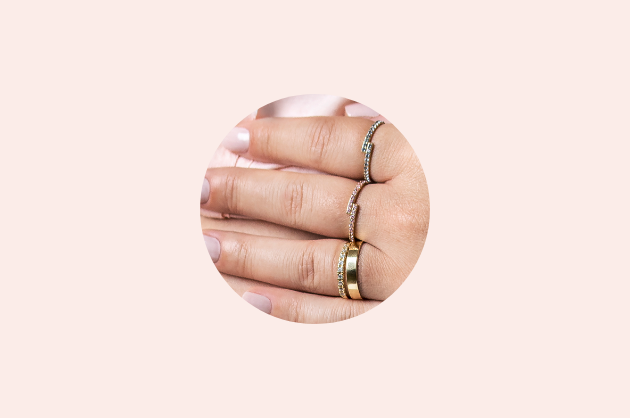 Mix de anéis com aparadores coloridos em vários dedos, em um deles tem uma aliança de ouro também 