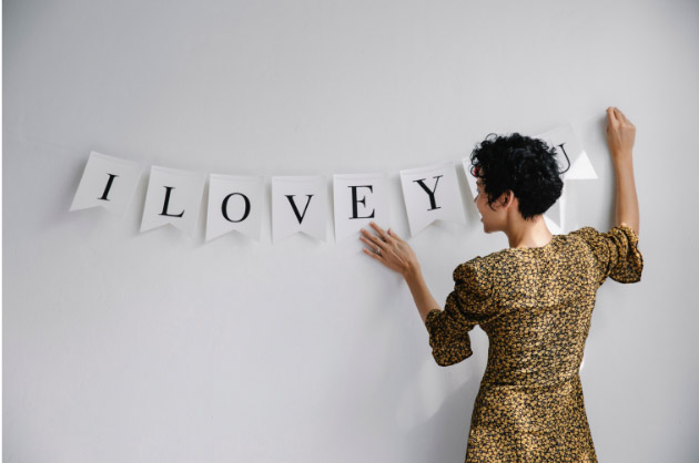 Frases que se complementam Mulher segurando bandeirinhas formando a frase “Eu te amo”, em inglês
