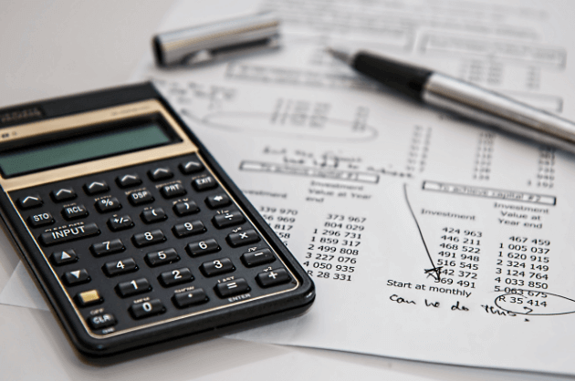 Papel com orçamento do casamento, uma calculadora e uma caneta