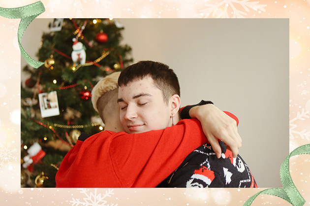 duas pessoas se abraçando na manhã de natal, ao fundo uma decoração natalina 
