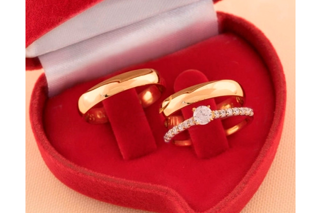 Alianças em Ouro 18K clássicas e anel solitário com várias pedras em uma caixinha de veludo vermelha