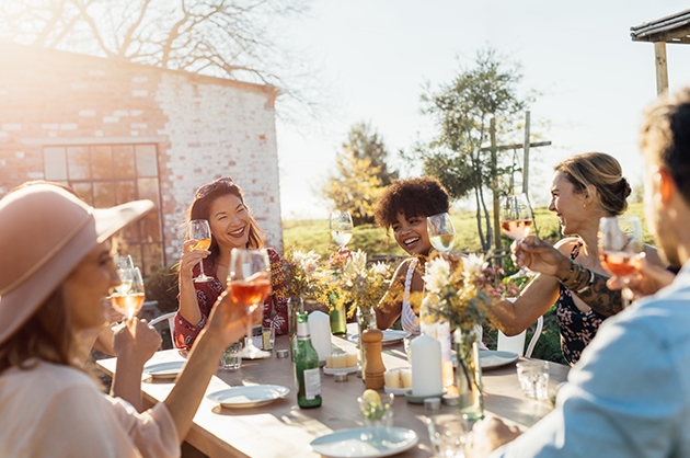 Mesa com amigas sorrindo e brindando ao sol