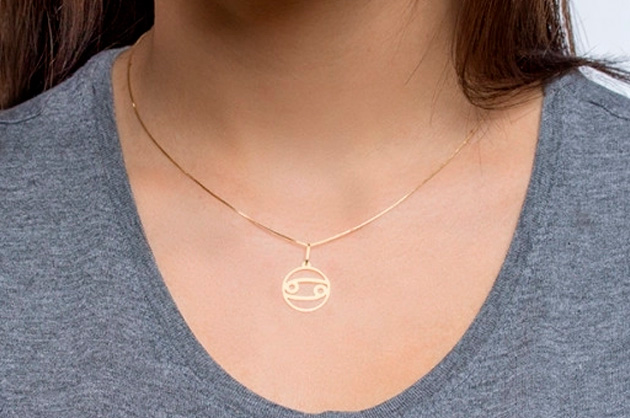 Modelo expondo colar de ouro com pingente com símbolo de signo de câncer