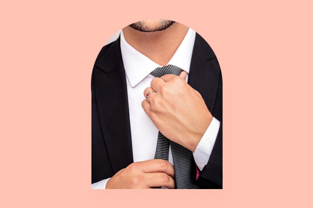 homem de terno ajustando a gravata com anel de formatura com pedra vermelha no dedo anelar esquerdo
