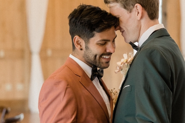Casal de noivos gays sorriem com as cabeças encostadas