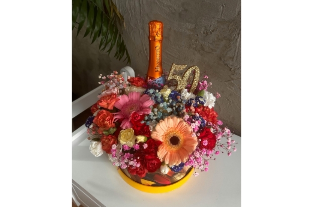 Arranjo de flores coloridas com garrafa de champanhe e numeral de 50
