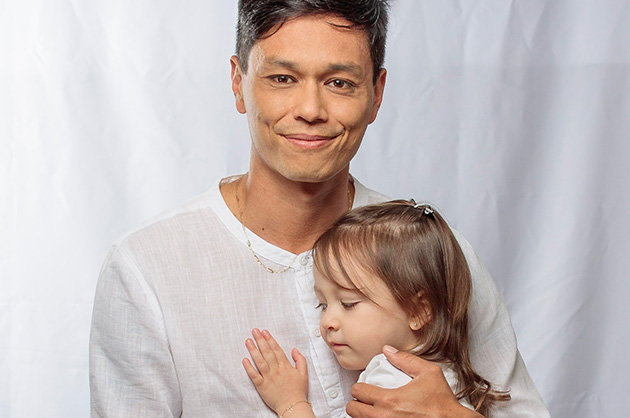 foto com pai e filha, filha criança encostada no peito do pai, ambos de roupas brancas 