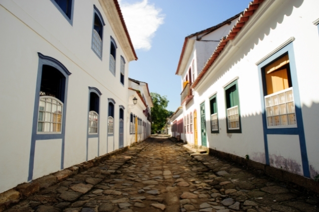 Rua de pedras com casinhas de paredes brancas e portas azuis em Paraty, RJ