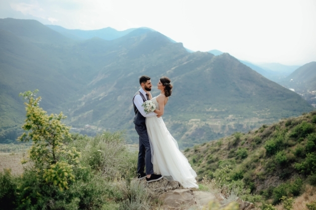 Casal de noivos se abraçam em uma paisagem montanhosa