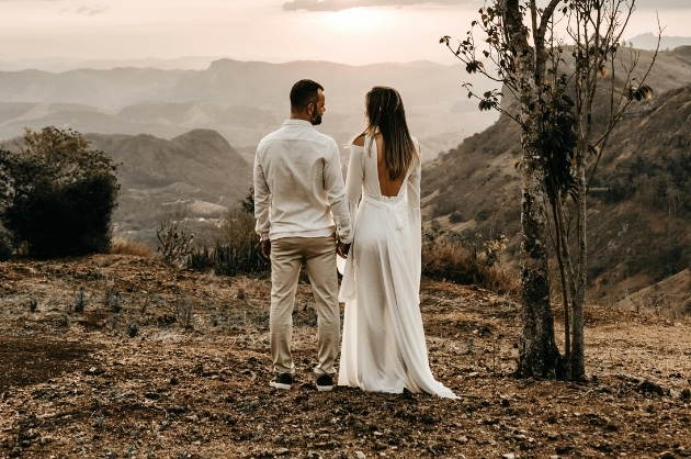 Casal de noivos em paisagem montanhosa de costas para a câmera