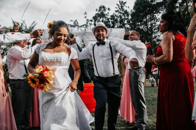 Casal de noivos saindo da cerimônia de casamento felizes acompanhados dos convidados