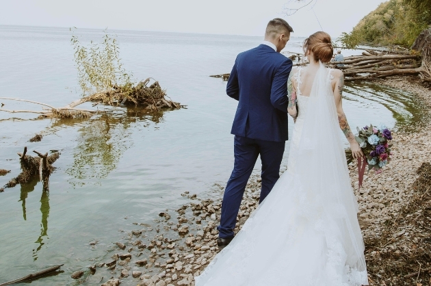Casal de noivos caminham à beira de um lago