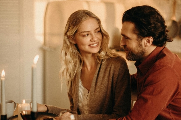 Casal se olha sorrindo em um jantar romântico